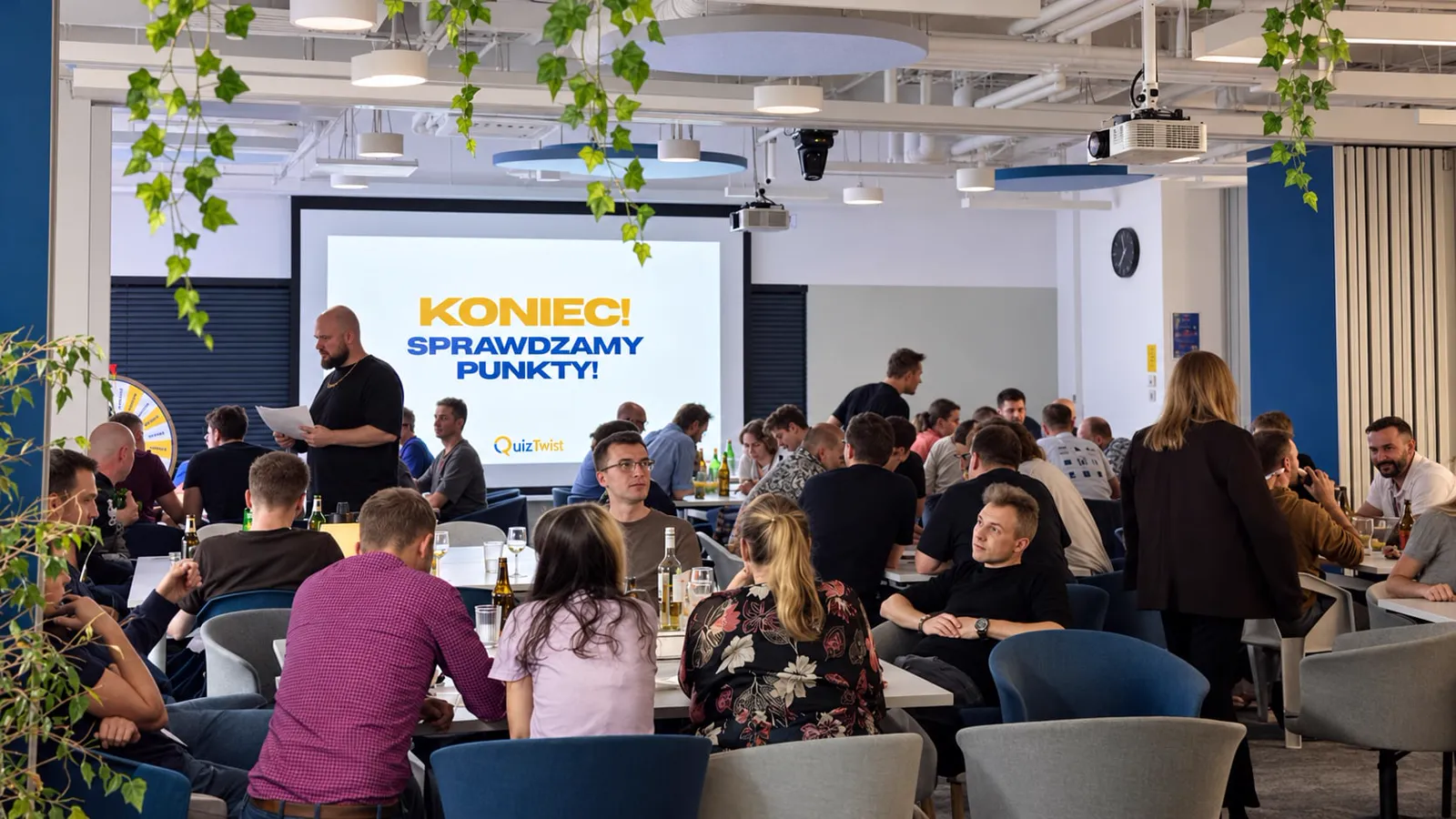 Pełna sala drużyn podczas quizu firmowego QuizTwist, na ekranie napis Koniec, sprawdzamy punkty